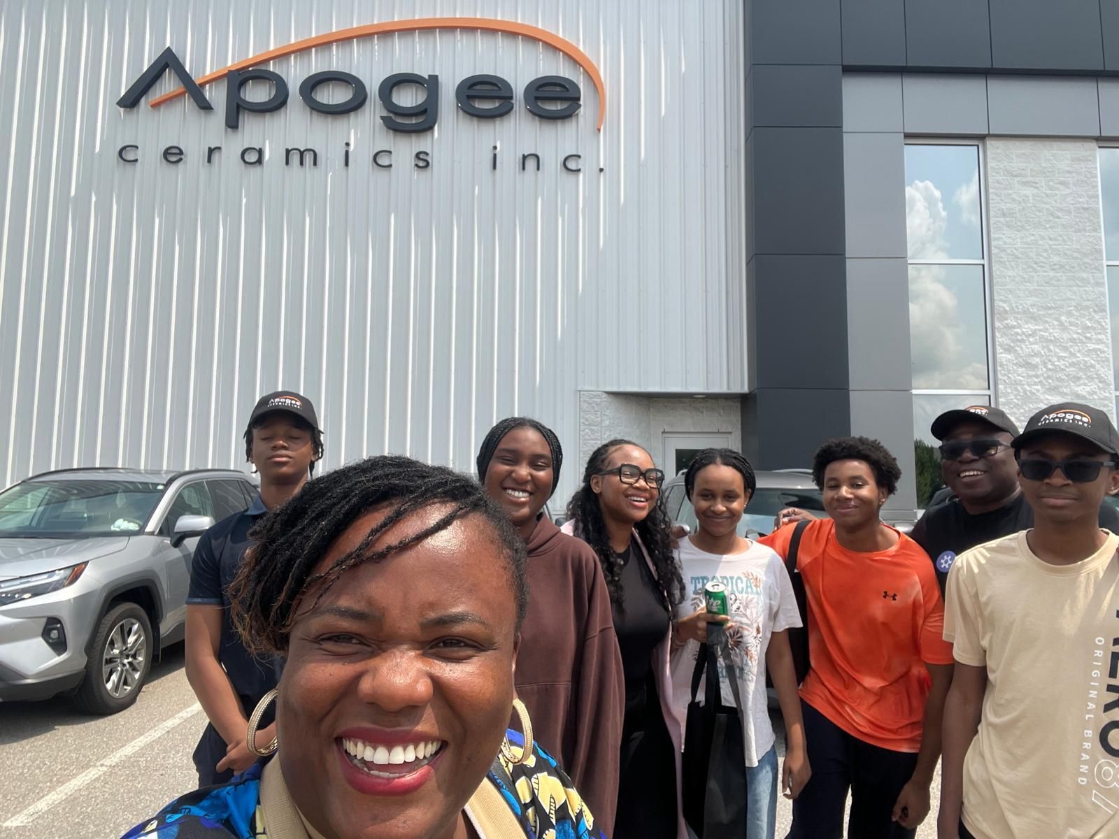 Black Youth in Business students and staff smile together outside Apogee Ceramics during an industry visit.